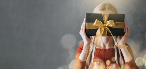 woman holding a box with a christmas present in her hands in front of her face