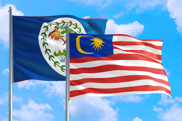 Malaysia and Belize national flag waving in the windy deep blue sky. Diplomacy and international relations concept.