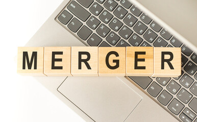 Word merger. Wooden cubes with letters isolated on a laptop keyboard. Business Concept image.