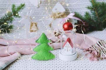 Merry Christmas, toy house, New Year decorations, illumination, spruce branches on the background of a knitted plaid, the concept of home comfort, congratulations on the winter holidays
