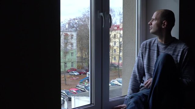 sad young man near the window with a view of the autumn Park and the street.