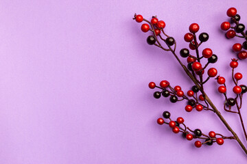 Christmas holidays composition with christmas decorations, red berries branches on purple background with copy space, top view