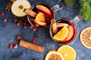 Two cups of christmas mulled wine or gluhwein with spices and orange slices on rustic table top view. Traditional drink on winter holiday