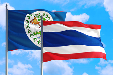 Thailand and Belize national flag waving in the windy deep blue sky. Diplomacy and international relations concept.