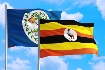 Uganda and Belize national flag waving in the windy deep blue sky. Diplomacy and international relations concept.