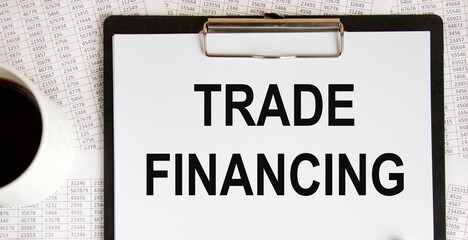Fototapeta premium On the letter tablet is the text of TRADE FINANCING, next to a mug of coffee.