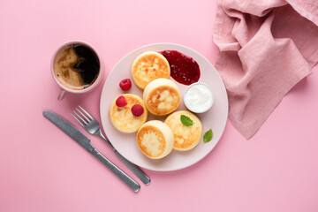 Syrniki, curd or cottage cheese pancakes with raspberry jam, sour cream and coffee on a pink background, top view