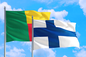 Finland and Benin national flag waving in the windy deep blue sky. Diplomacy and international relations concept.