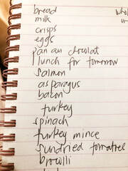 A handwritten shopping list in a spiral bound notepad