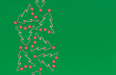 Candy canes on a green background with copy space at side. Christmas or New Year flat lay.