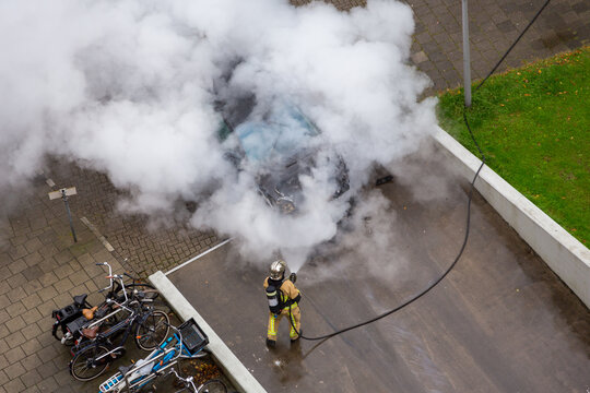 A firefighter creates a lot of smoke and steam when putting out a car in the driveway of a parking garage on Fregelaan in Amsterdam the Netherlands.