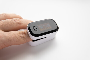 A pulse oximeter measure pulse rate, oxygen saturation level on male finger. Device shows normal...