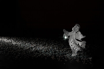 Figurine of an angel in backlight on a dark background. Happy Christmas.