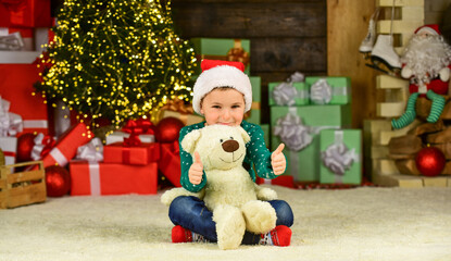 Fototapeta na wymiar Kid enjoy the holiday. kid hold bear toy gift. toy shop is open at xmas. merry christmas. happy new year. happy child santa hat. son ready to celebrate winter holidays. small boy excited with present
