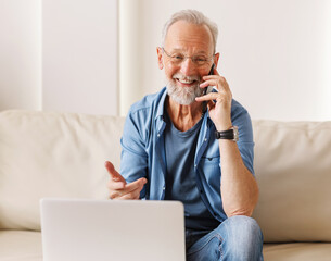 Delighted elderly freelancer speaking on smartphone.