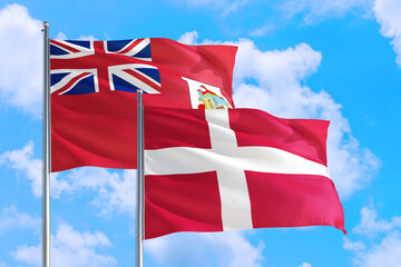 Denmark and Bermuda national flag waving in the windy deep blue sky. Diplomacy and international relations concept.