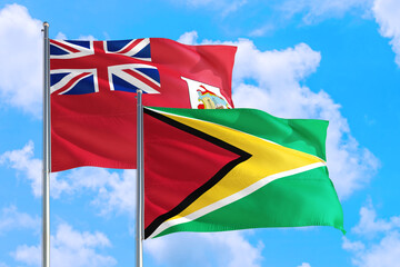 Guyana and Bermuda national flag waving in the windy deep blue sky. Diplomacy and international relations concept.