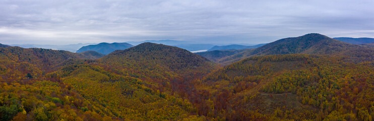 Fototapeta premium Visegrad, Hungary - Aerial panoramic view of autumn colored Visegrád hills with danube bend at the background