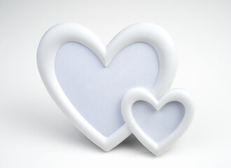 Two white hearts in a close-up frame on a light background. Side view. Concept of holiday backgrounds.