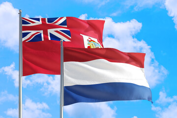 Netherlands and Bermuda national flag waving in the windy deep blue sky. Diplomacy and international relations concept.