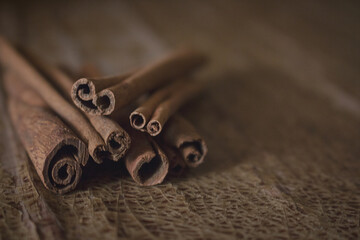 Folded cinnamon sticks isolated on vintage wooden background with copy space. Concept of health benefits of spices for overlay on product presentation, advertising, mockup, template and wallpaper.
