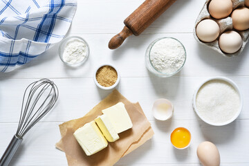 Fototapeta na wymiar Baking ingredients: flour, eggs, sugar with a rolling pin on a light white wood background.