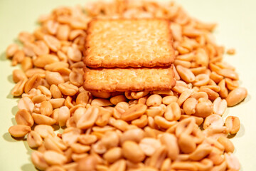 Appetizing brown dry cracker on scattered roasted peanuts