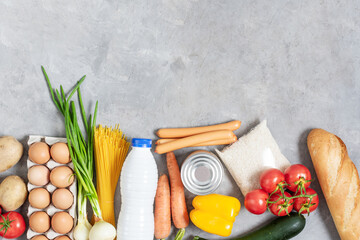 Variety of vegetables and grocery products on grey concrete table top view.
