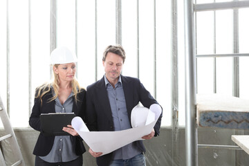 Fototapeta premium man and woman architects or engineers work together discussing with blueprint in the inside the construction building site