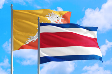 Costa Rica and Bhutan national flag waving in the windy deep blue sky. Diplomacy and international relations concept.