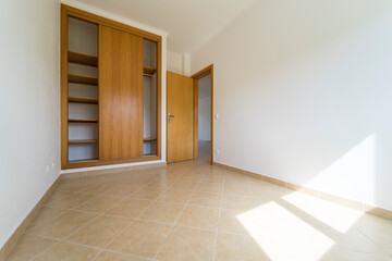 Empty room with dark wooden floating laminate flooring and wardrobe. House interior, wide bedroom...