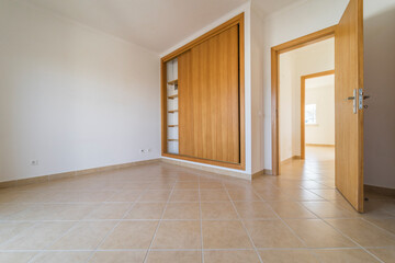 Empty room with dark wooden floating laminate flooring and wardrobe. House interior, wide bedroom space. Newly recently painted new apartment or house. Wood floor. Real state and property management