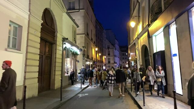 Time lapse footage of people walking on streets of famous shopping neighborhood called "Le Marais" in Paris. Lifestyle and culture concept. It is a winter night. Camera moves forward.
