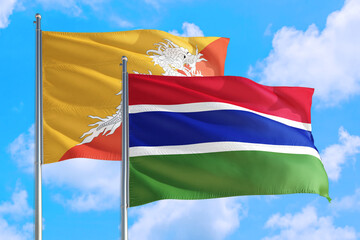 Gambia and Bhutan national flag waving in the windy deep blue sky. Diplomacy and international relations concept.