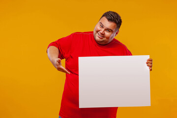 Fat man in red t-shirt displaying a white banner ad isolated over a yellow background.