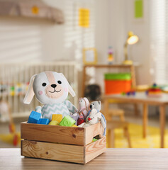 Set of different cute toys on wooden table in children's room