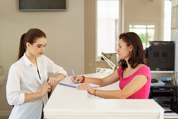 Lovely receptionist working with client at desk in beauty salon