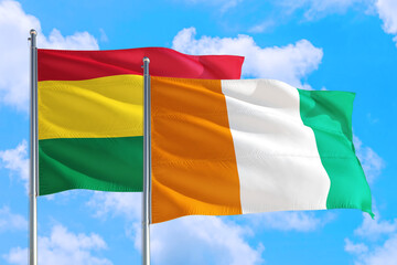 Cote D'Ivoire and Bolivia national flag waving in the windy deep blue sky. Diplomacy and international relations concept.