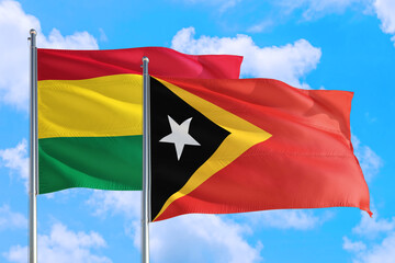 Fototapeta na wymiar East Timor and Bolivia national flag waving in the windy deep blue sky. Diplomacy and international relations concept.