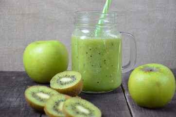 Green healthy smoothie in glass jar: banana, kiwi, green apple on rustic background