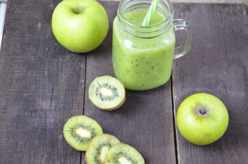 Green healthy smoothie in glass jar: banana, kiwi, green apple on rustic background