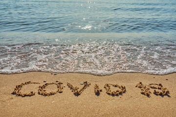 Covid 19 inscription on a tropical sandy beach with waves and foam on a background.