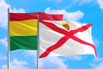 Jersey and Bolivia national flag waving in the windy deep blue sky. Diplomacy and international relations concept.