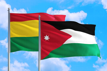 Jordan and Bolivia national flag waving in the windy deep blue sky. Diplomacy and international relations concept.