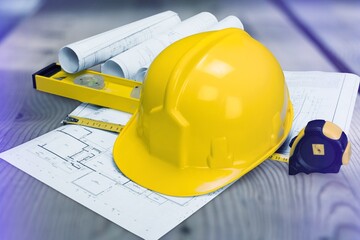 Paper blueprints, a yellow hardhat and tools