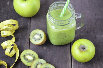 Green healthy smoothie in glass jar: banana, kiwi, green apple on rustic background