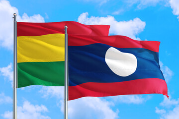 Laos and Bolivia national flag waving in the windy deep blue sky. Diplomacy and international relations concept.