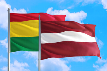Fototapeta na wymiar Latvia and Bolivia national flag waving in the windy deep blue sky. Diplomacy and international relations concept.