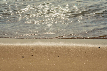 Blurred wave with foam on a sandy beach as a natural background/texture.