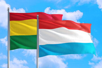 Luxembourg and Bolivia national flag waving in the windy deep blue sky. Diplomacy and international relations concept.